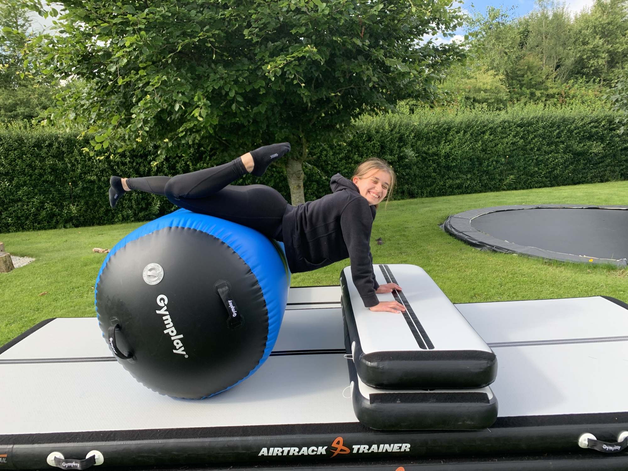 Studiefoto af en grå og sort GymPlay airtrack med en elektrisk pumpe ved siden af